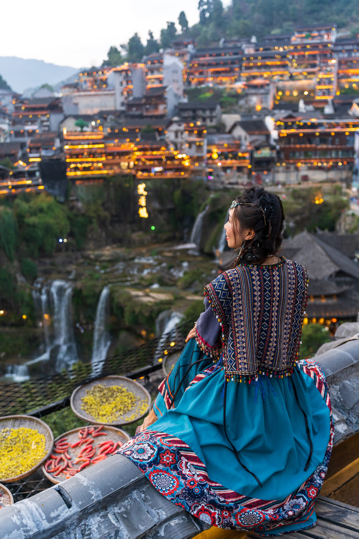 una mujer sentada viendo el paisaje de la ciudad de lijiang de fondo