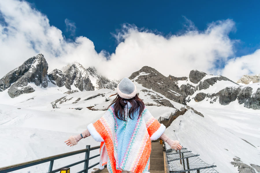 foto de una niña de espaldas con un fondo de una. montaña en yulongshang